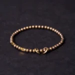 Tibetan copper brass couple bracelet flat lay with toggle clasp design, showing polished round beads on dark background