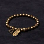 Handmade tibetan copper brass luck bracelet with engraved good luck tag and triangle charm, overhead flat lay view