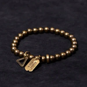 Handmade tibetan copper brass luck bracelet with engraved good luck tag and triangle charm, overhead flat lay view