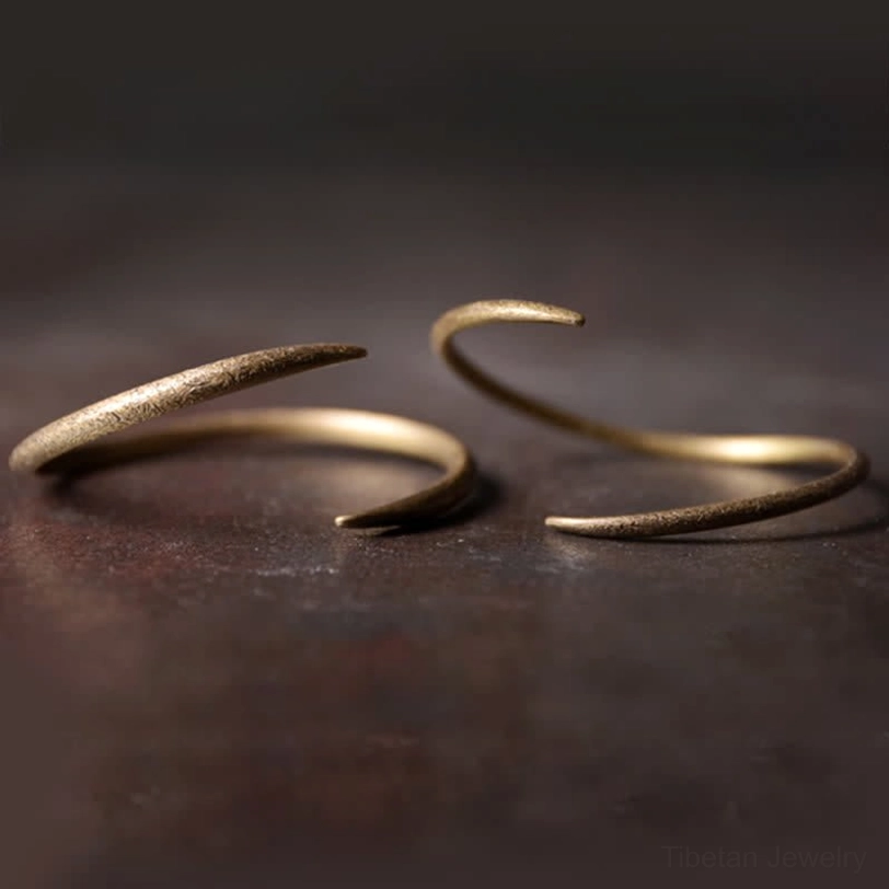 Two pairs of open copper claw cuff bracelets overhead flat lay, matte bronze-gold finish, minimalist Tibetan-inspired design