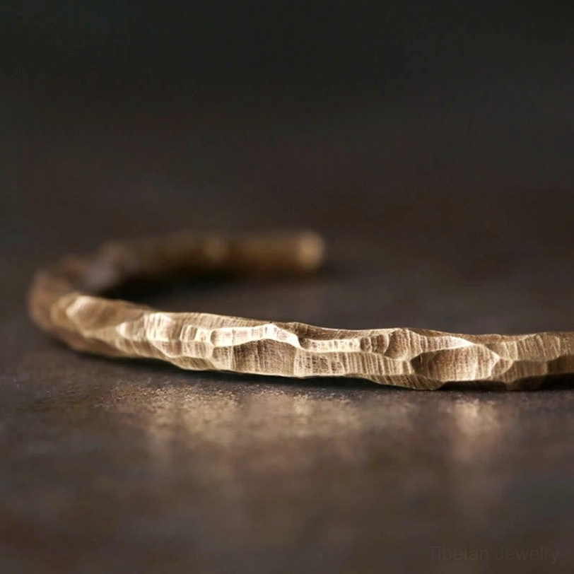 Tibetan hammered copper bracelet close-up flat lay showing distinct bumpy texture and warm metallic brass color