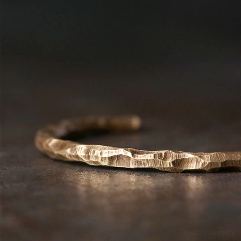 Close-up side view of Tibetan copper hammered cuff bracelet displaying detailed bumpy texture and warm gold tone