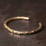 Tibetan hammered copper cuff bracelet top-down flat lay showing textured brass surface on rustic metal background