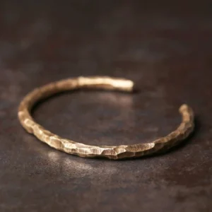 Tibetan hammered copper cuff bracelet top-down flat lay showing textured brass surface on rustic metal background