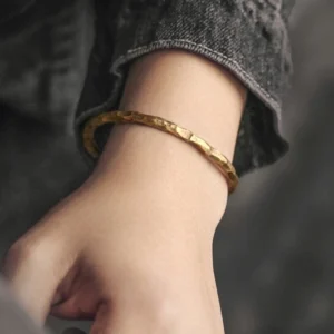 Hammered copper Tibetan bracelet worn on wrist with denim sleeve showing metallic finish and bumpy texture detail