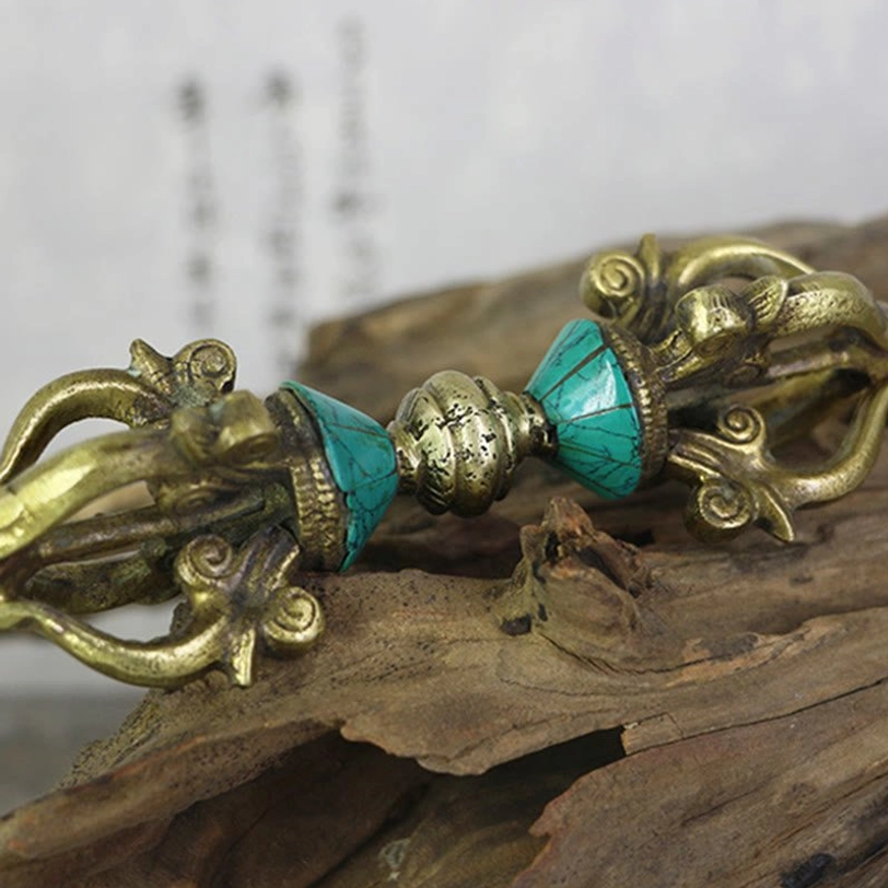 Low angle view of handcrafted Tibetan five-prong copper dorje with worn brass patina on wooden background