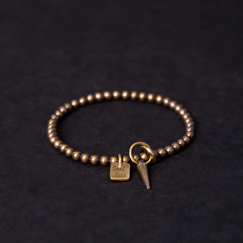 Tibetan copper prosperity bracelet with good luck charm flat lay top view featuring antique bronze beads and engraved square pendant