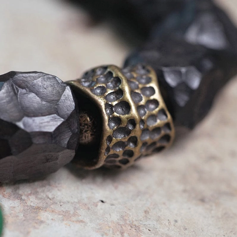 Hollow carved bronze copper spacer with dark wooden beads side macro view