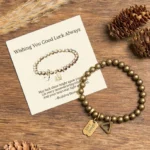 Tibetan copper luck bracelet with engraved good luck charm tag, flat lay on wooden surface with natural decor