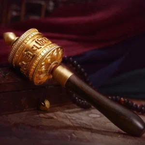 Golden polished tibetan copper prayer wheel with engraved om mani padme hum mantra and wooden grip detail