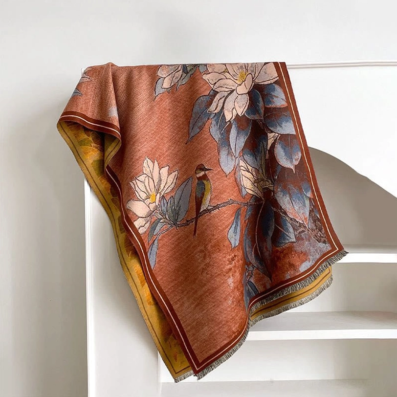 Coral and blue Tibetan scarf with foliage and magnolia print displayed flat on shelf - reversible sides