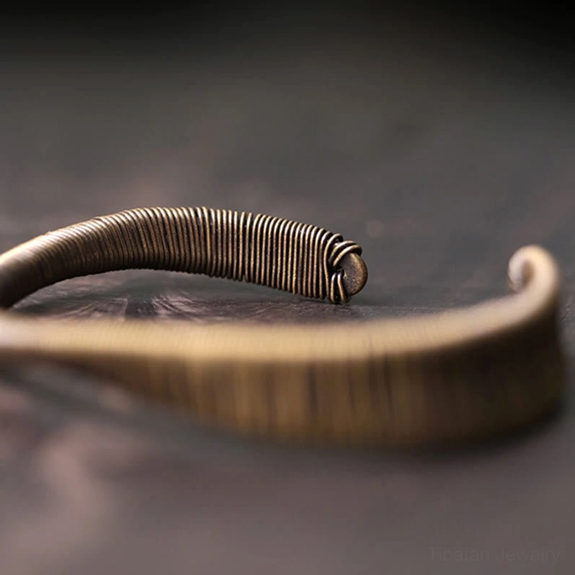 Low overhead close-up of curved open ends and tightly coiled wire finish on Tibetan prosperity cuff bracelet