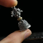 Tibetan 925 sterling silver dorje bell pendant close-up view with hand, showing intricate carved patterns and antique silver finish