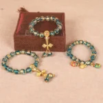 Tibetan Buddhist beaded bracelet collection featuring gold swallowing beast and vajra charms displayed on jewelry box