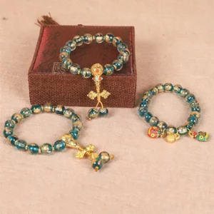 Tibetan Buddhist beaded bracelet collection featuring gold swallowing beast and vajra charms displayed on jewelry box
