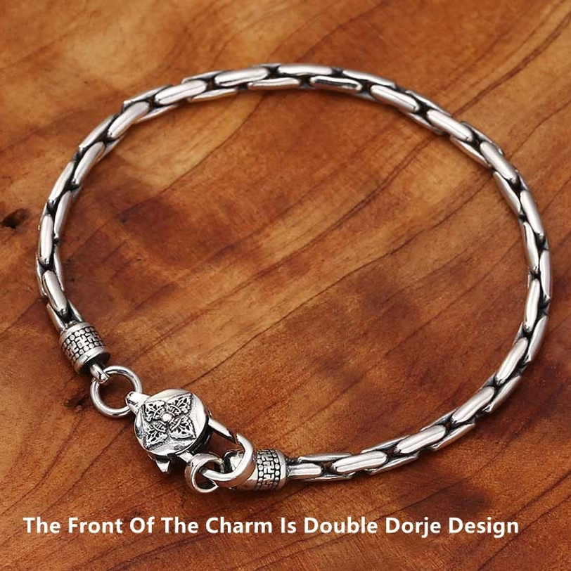Tibetan double dorje bracelet flat lay showing front charm engraving on wooden background