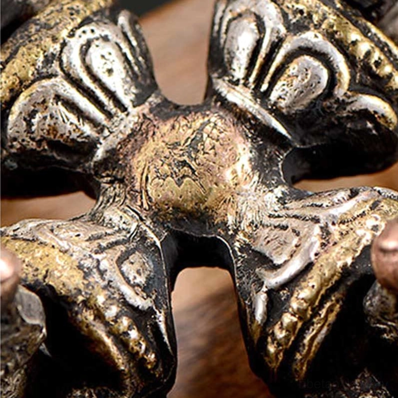 Close-up front view of central dorje section revealing gilded bronze accents and intricate embossed Buddhist carvings