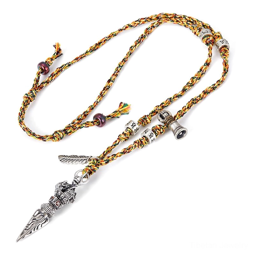 Overhead flat lay of handmade Tibetan silver Dorje necklace with multicolor braided cord and small colored beads on plain white background