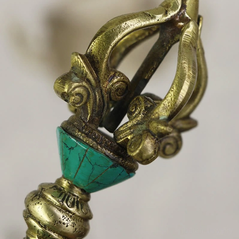 Macro photography of conical turquoise inlay and ornate brass collar on Tibetan copper dorje