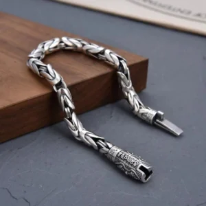 Tibetan Buddhist copper mantra bracelet low angle side view displaying dual engraved metal clasps and antique silver finish on dark tabletop