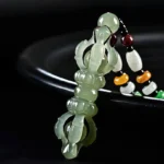 Cyan Hetian Jade Dorje Vajra pendant with translucent carving on black background, three-quarter close-up view