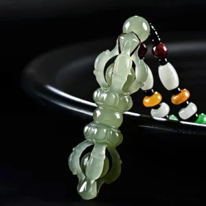 Cyan Hetian Jade Dorje Vajra pendant with translucent carving on black background, three-quarter close-up view