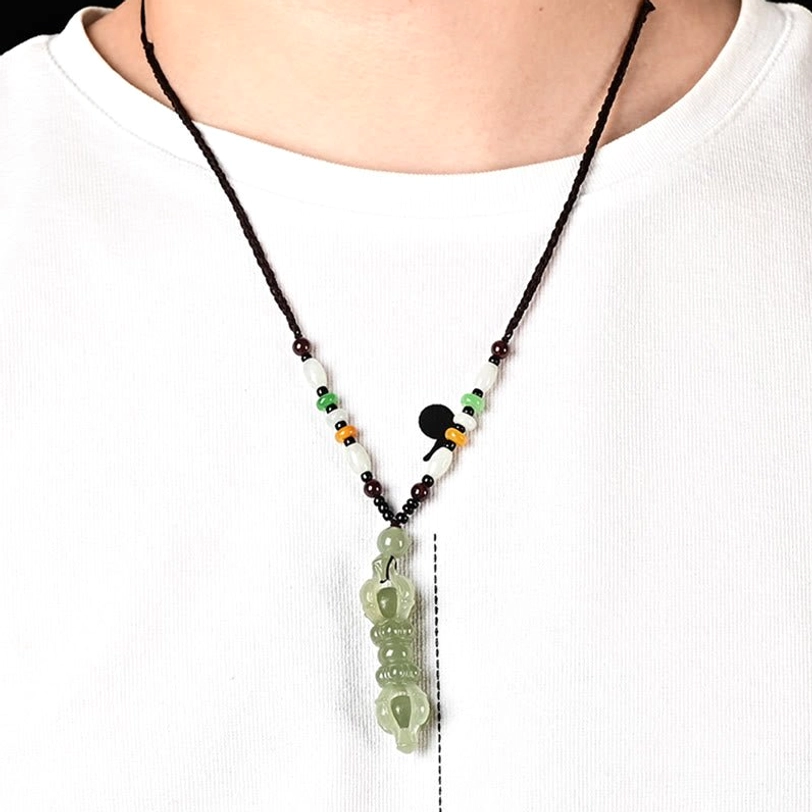 Tibetan Dorje Vajra necklace worn on neck, black braided cord with colorful spacer beads, pendant resting on chest against white shirt