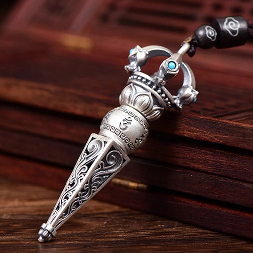 Right side oblique angle of Tibetan Dorje Vajra necklace showing openwork crown design, hollowed scroll tips, and engraved Sanskrit mantra details
