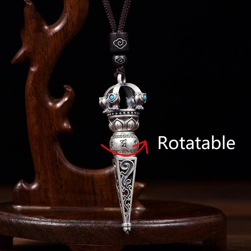 Front view of rotating Tibetan Dorje Vajra pendant on wooden display stand with detailed scroll carvings, turquoise inlays, and marked rotating mechanism
