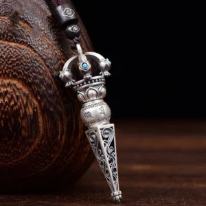 Tibetan Dorje Vajra rotating pendant necklace with turquoise inlays and engraved Om Mani Padme Hum mantra, left front oblique view showing intricate scroll carvings and copper finish