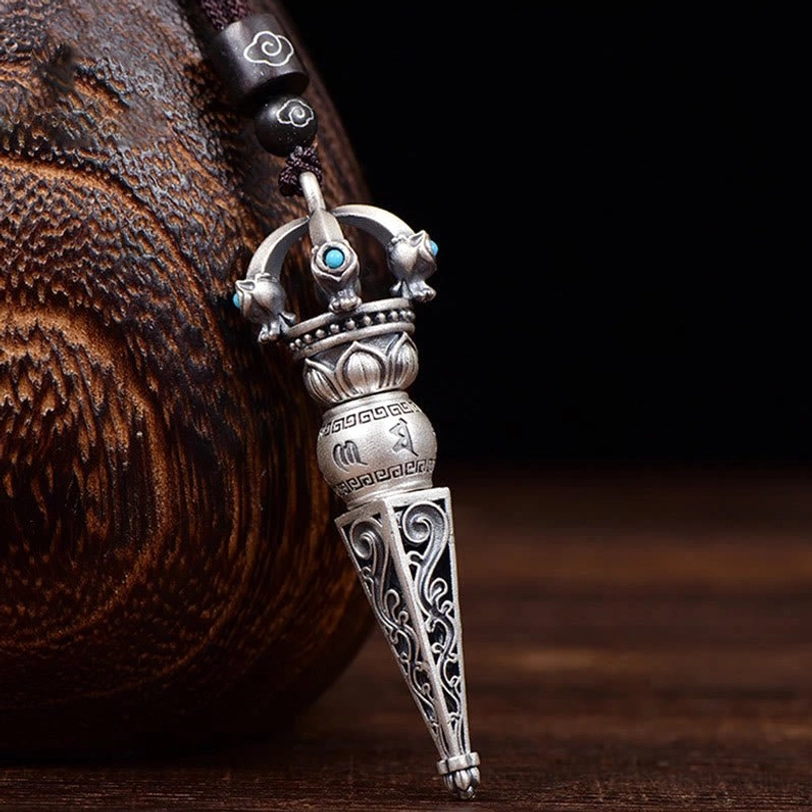 Tibetan Dorje Vajra rotating pendant necklace with turquoise inlays and engraved Om Mani Padme Hum mantra, left front oblique view showing intricate scroll carvings and copper finish