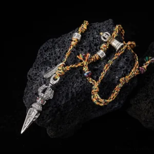 Tibetan 925 sterling silver Dorje Vajra necklace with five-color braided cord displayed on black volcanic stone, showing intricate handmade pendant details