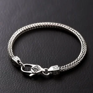Tibetan Double Dorje Vajra Bracelet - Flat lay with silver braided wheat chain design and carved clasp on dark leather