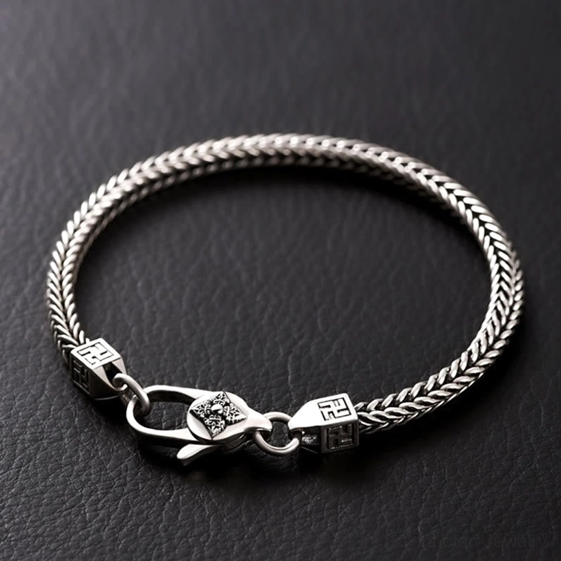 Tibetan Double Dorje Vajra Bracelet - Flat lay with silver braided wheat chain design and carved clasp on dark leather