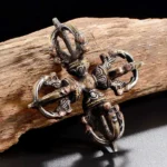Handcrafted Tibetan double dorje vajra in aged copper and iron, top-down flat view showcasing intricate religious carvings and mixed metal patina