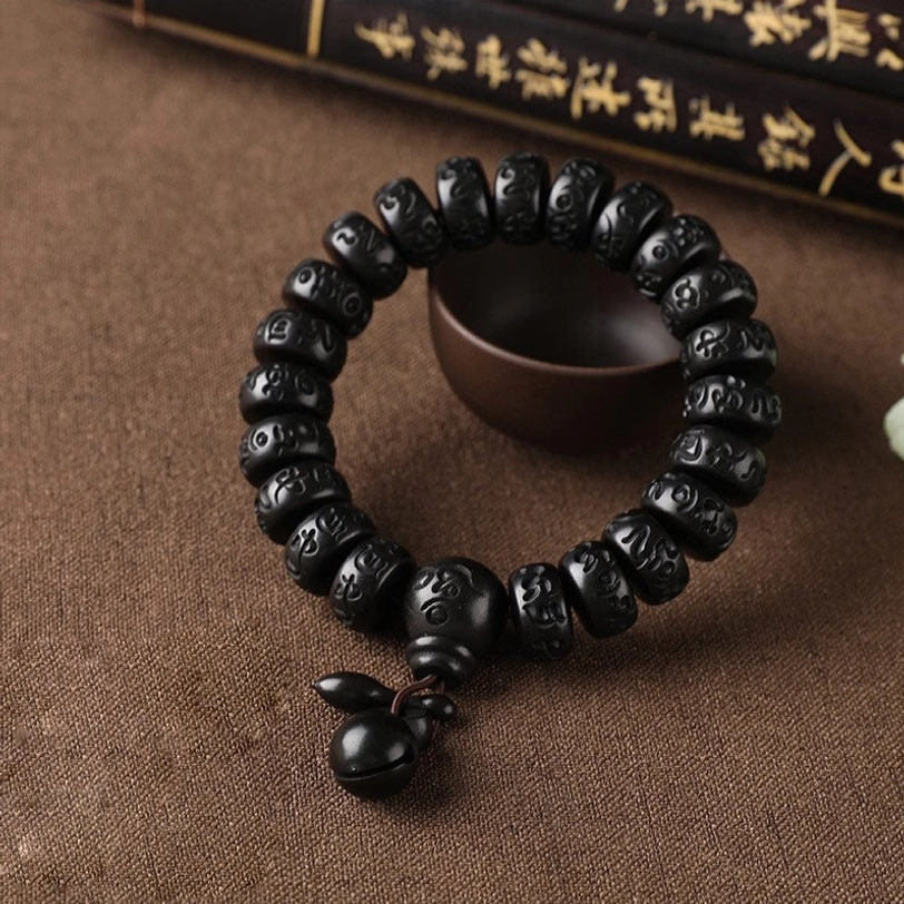 Double-strand Tibetan prayer bracelet with two rows of mantra beads and dual wooden bell pendants on traditional background