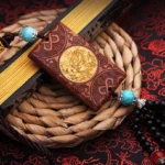 Tibetan rosewood and boxwood dragon car hanging with carved floral trim and golden dragon inlay, displayed on woven coaster with red floral cloth