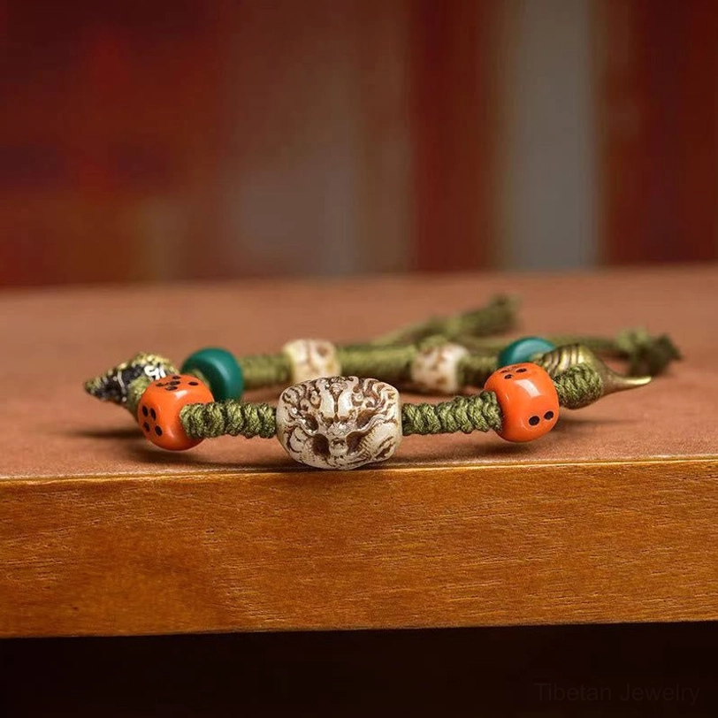 Multiple handmade Tibetan dragon bracelets with matching green rope and mixed ethnic decorative beads on wooden surface