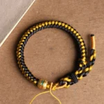 Tibetan black gold dragon scale om mani padme hum bracelet overhead flat lay view showing detailed woven rope pattern