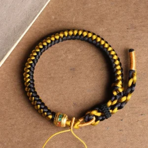 Tibetan black gold dragon scale om mani padme hum bracelet overhead flat lay view showing detailed woven rope pattern