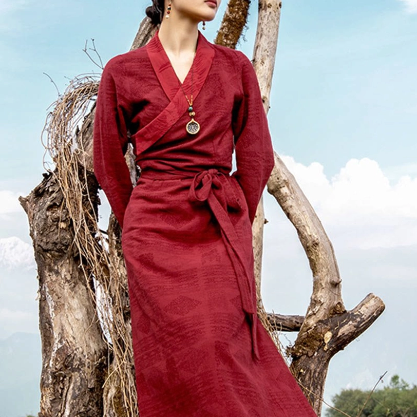 Close-up side view of Tibetan chuba dress showing cross-wrap neckline detail, waist tie, and pendant ornament with burgundy woven fabric