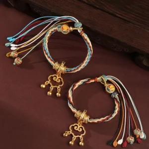 Handcrafted Dunhuang deer auspicious cloud healing bracelet with gold bell lock on dark wood surface, multicolor braided cord detail