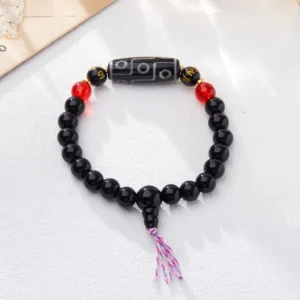 Tibetan nine-eye dzi bead bracelet flat lay showing intricate beadwork and red accent stones