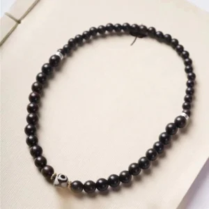 Double wrap ebony wood and dzi bead bracelet displayed in looped formation, studio flat lay showing complete design with silver accents