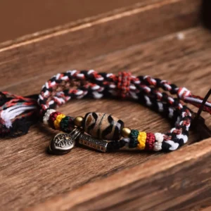 Overhead view of double-wrap Tibetan Dzi bead bracelet with striped woven rope, patterned Dzi bead, and decorative colored spacer beads