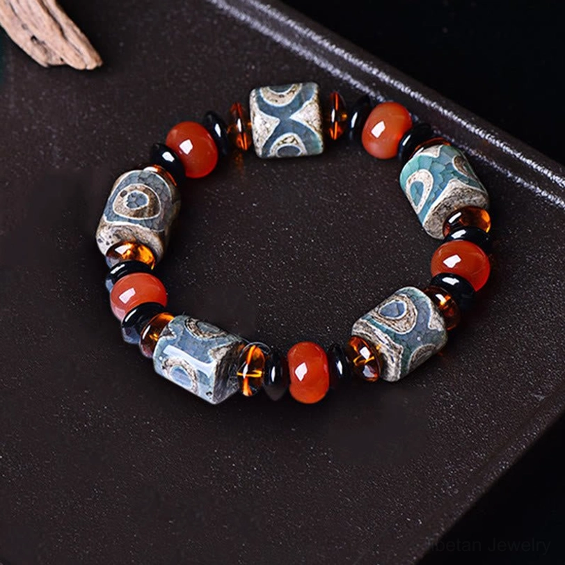 Three-Eye Dzi Bead Agate Bracelet - overhead flat lay on dark tray showing full circular bead arrangement with authentic etched patterns and natural stone variations