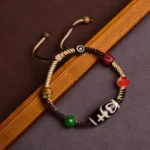 Handmade Tibetan nine-eye dzi bead bracelet with adjustable braided rope and multi-color accent beads, side view