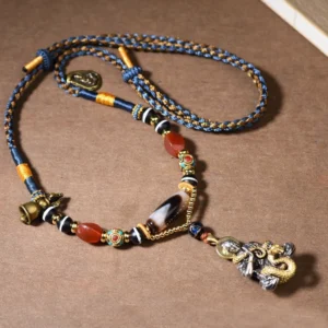 Tibetan snake Buddha Dzi bead necklace with woven rope and metal fittings, flat lay overhead shot showing full necklace design