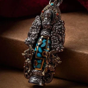 Tibetan nine-eye dzi bead Buddha turquoise pendant with intricate two-tone metalwork and carved floral patterns on wooden surface
