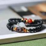 Tibetan dzi bead double wrap bracelet with ebony wood beads and hand-painted three-eye dzi stone - top view on hardcover book